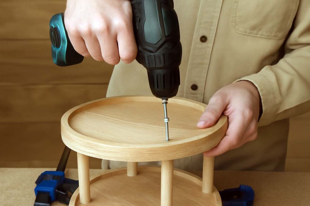 Close up of using screws to secure the top and bottom trays of a 2 tier tray stand.