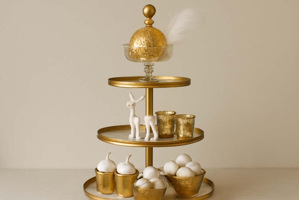 Three-tier tray decorated with gold vessels, white reindeer, and metallic votives