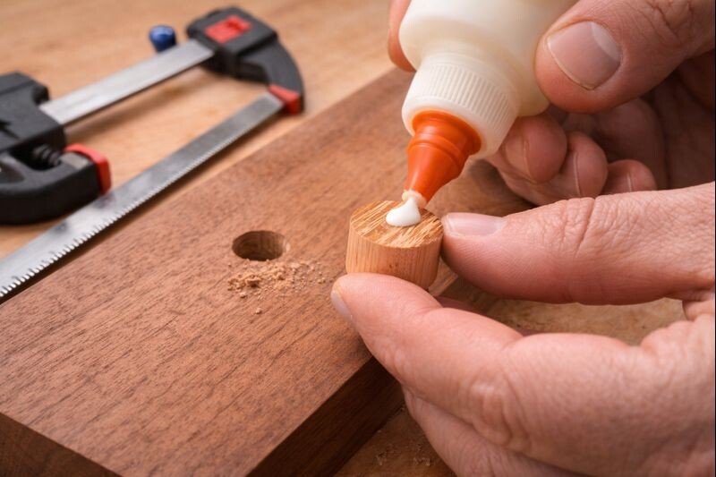 applying glue to a face grain wood plug repair