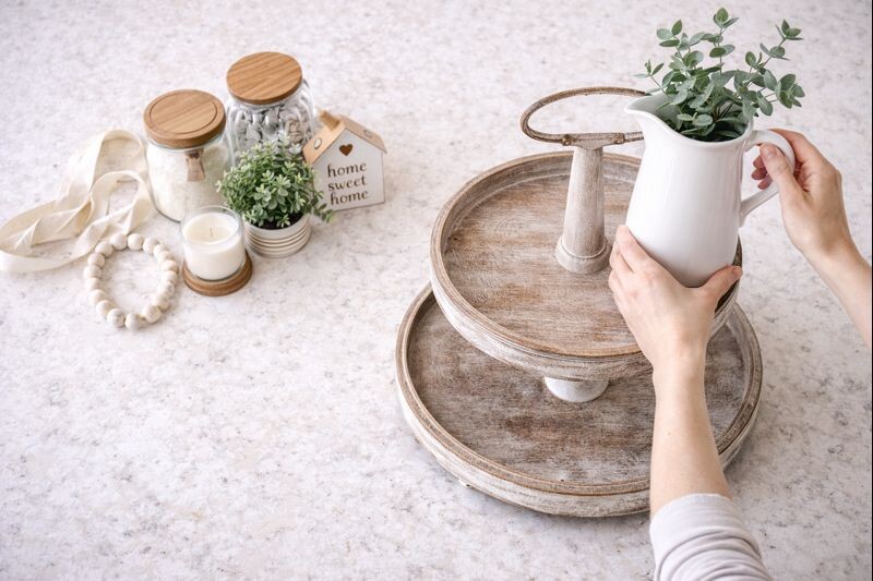 hands placing tall decor on top tier