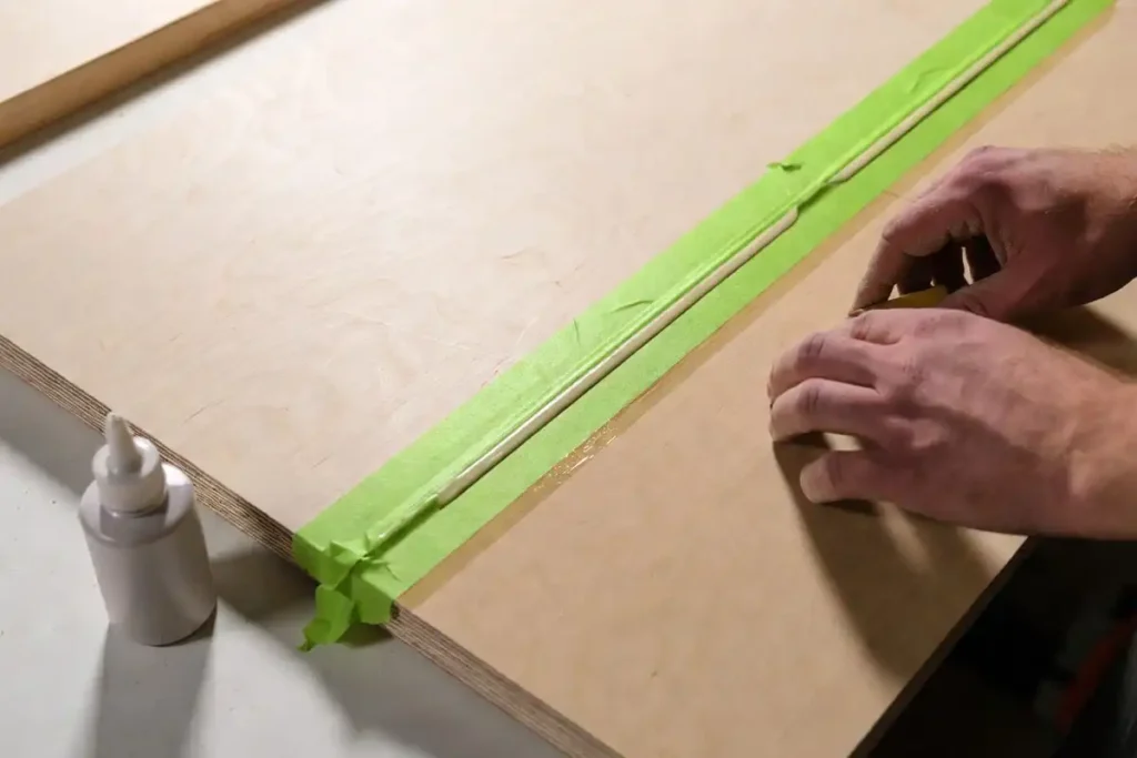 tape masking a narrow glue strip on a finished plywood panel